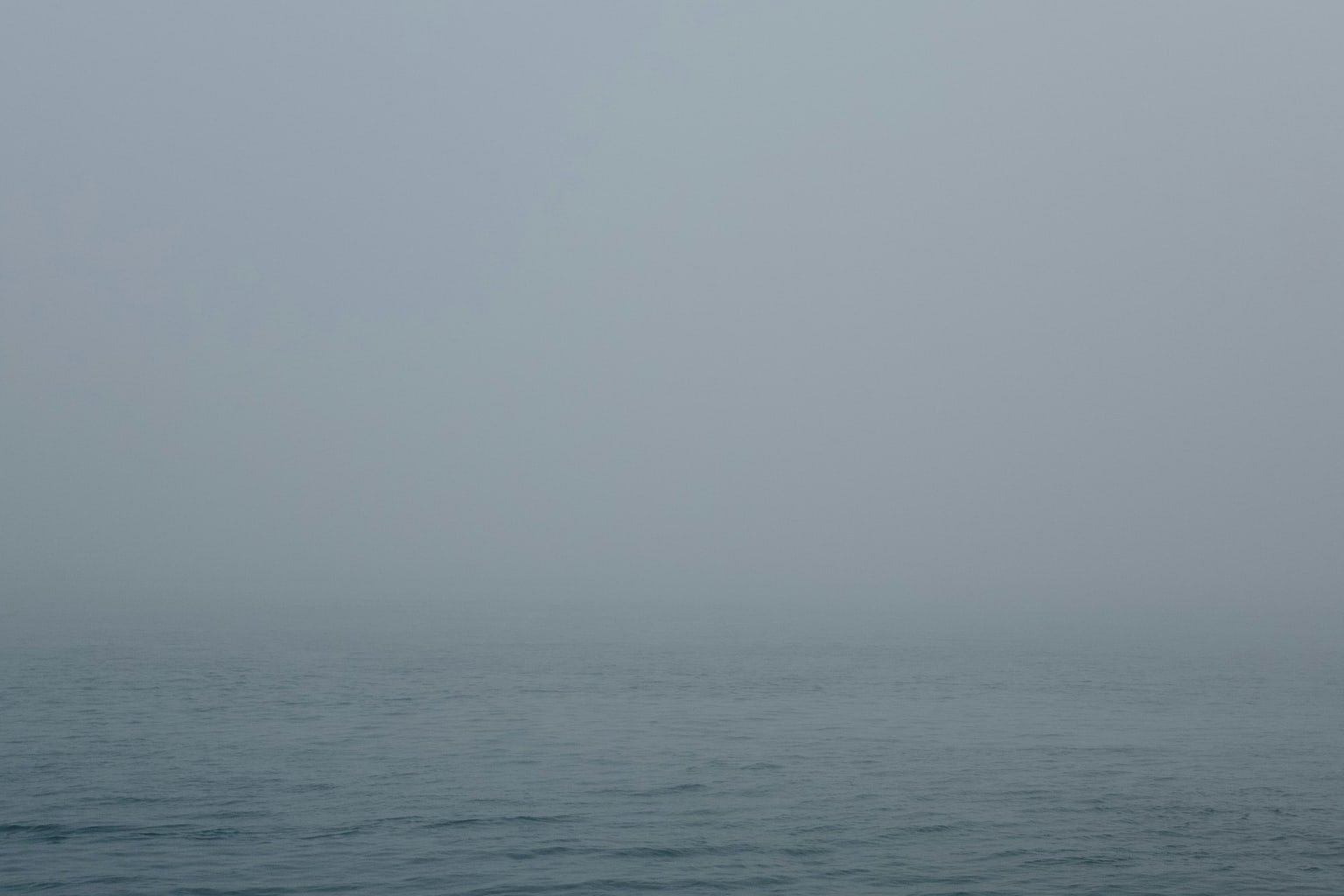 Mar calmo desaparecendo na neblina, sem horizonte visível